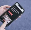 Hand houdt smartphone vast met een pagina over Brugse rondvaarten op het scherm.